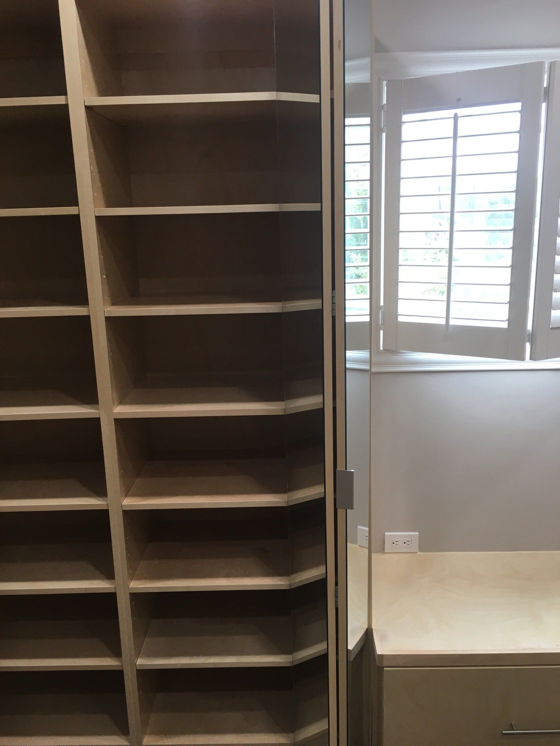 a custom walk-in closet filled with shelves and shoe cabinet