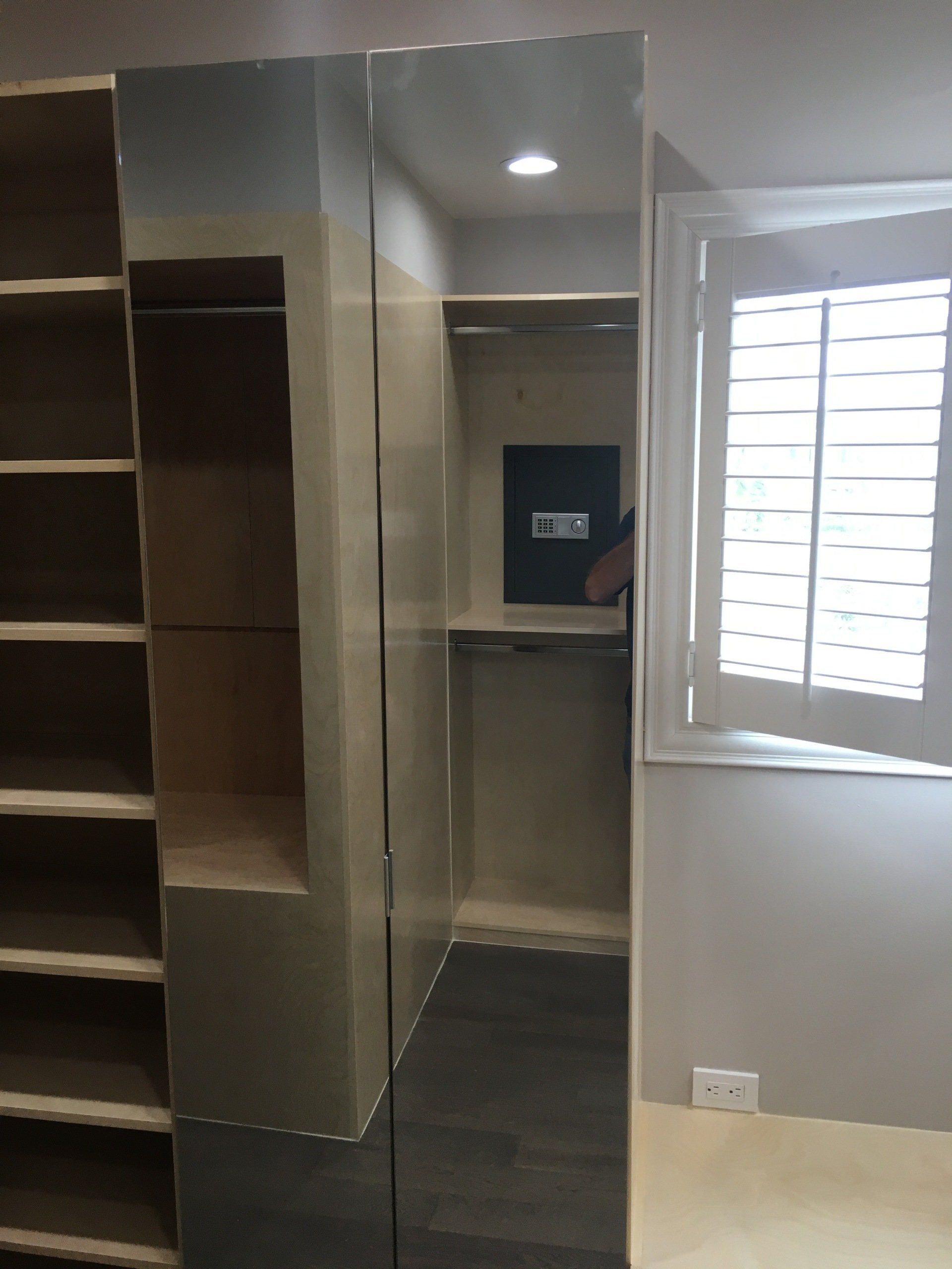 a custom walk-in closet with mirrored door cabinet