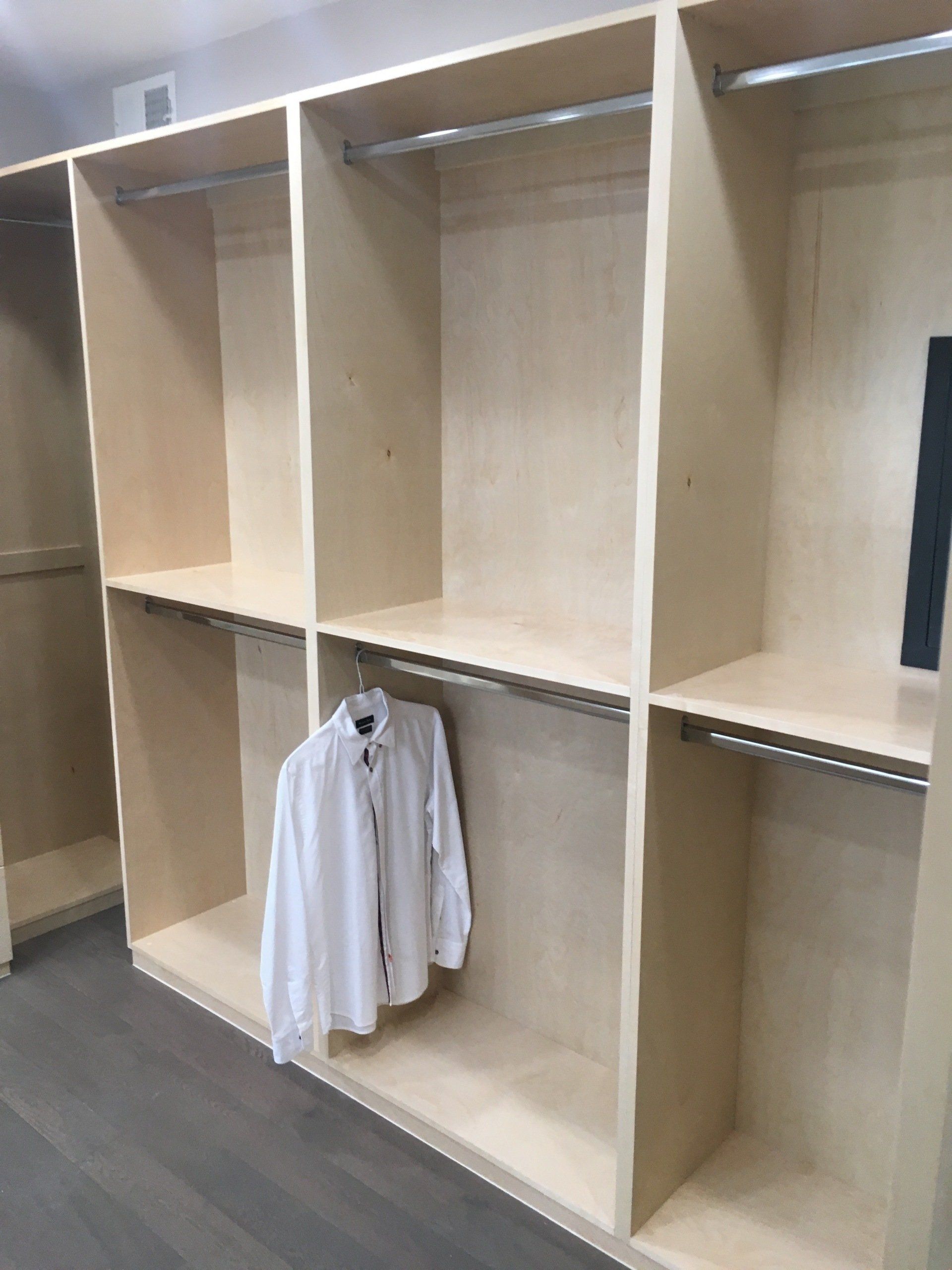 an empty walk-in closet filled with hanging rods cabinet