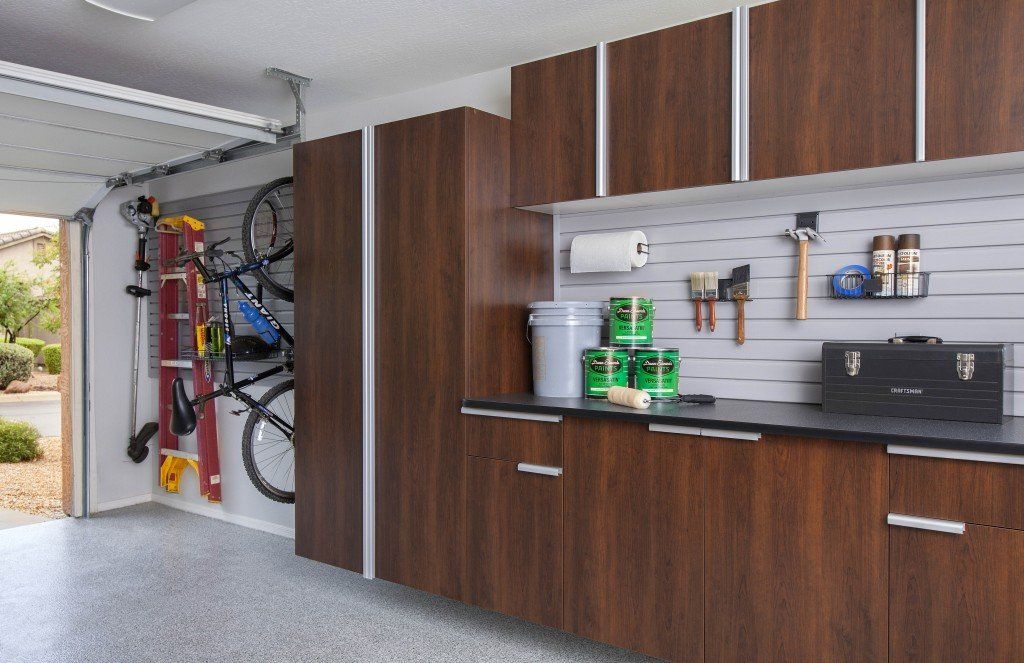 a garage with wooden cabinets , a bicycle rack , a ladder , and a workbench .