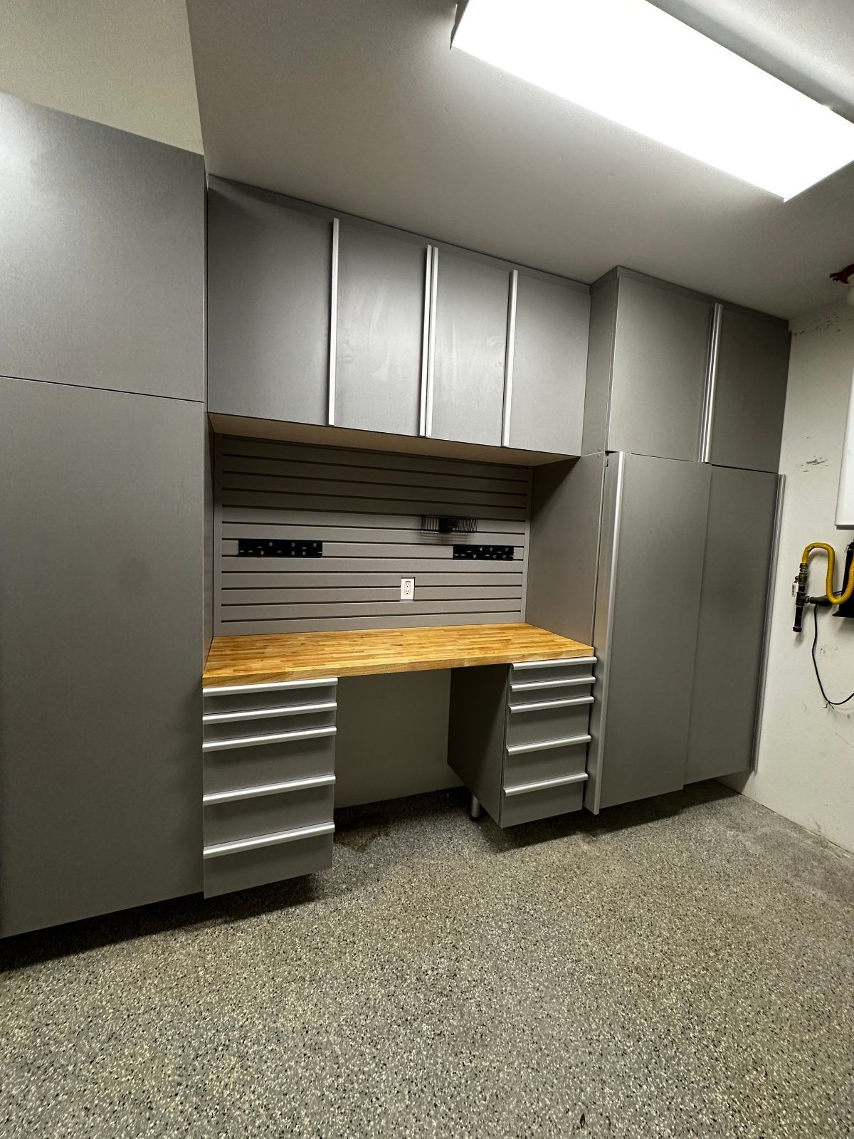 Gray garage workshop with cabinets, wooden countertop, and drawers.