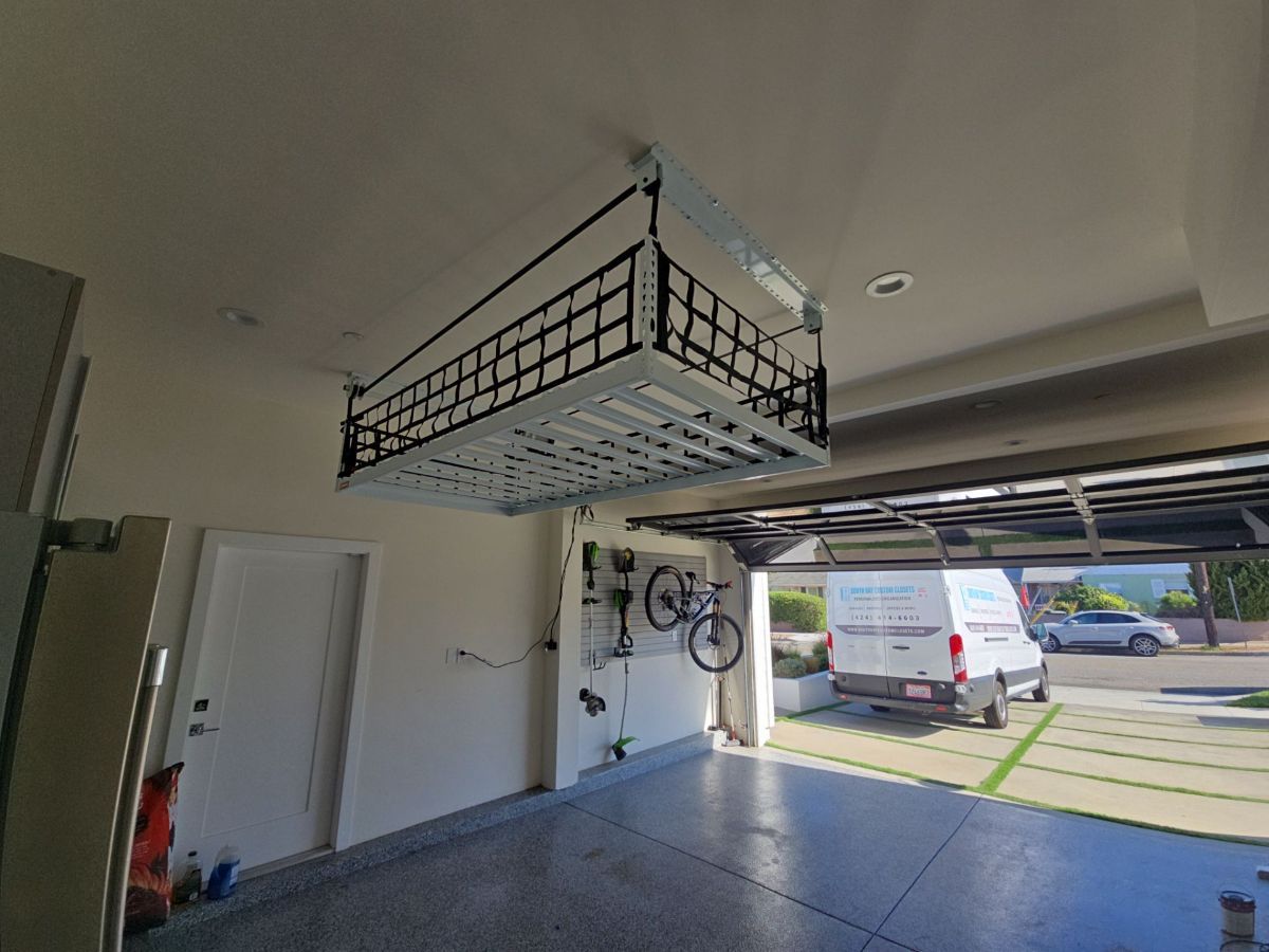 Garage with a suspended storage rack. Open door with a van visible outside.