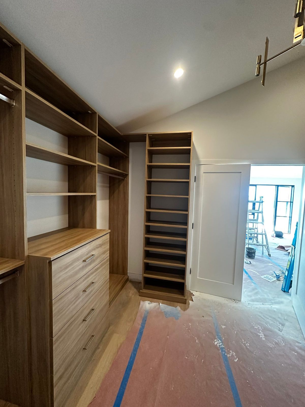 Custom wooden closet with shelving, drawers, and shoe storage, near a white door, indoors.