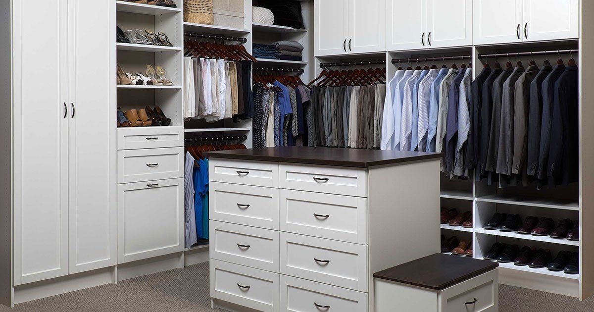 walk-in closet with white cabinets, drawers, and a center island cabinet