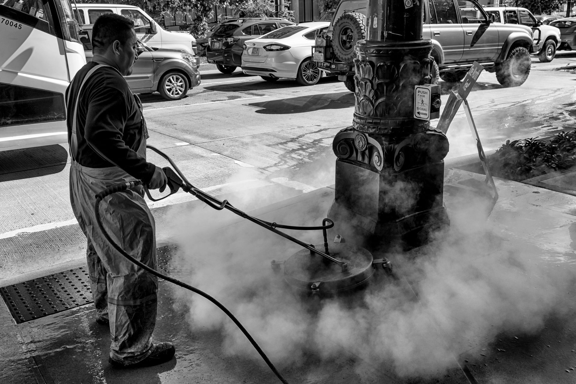 A man is cleaning a street light with a high pressure washer.