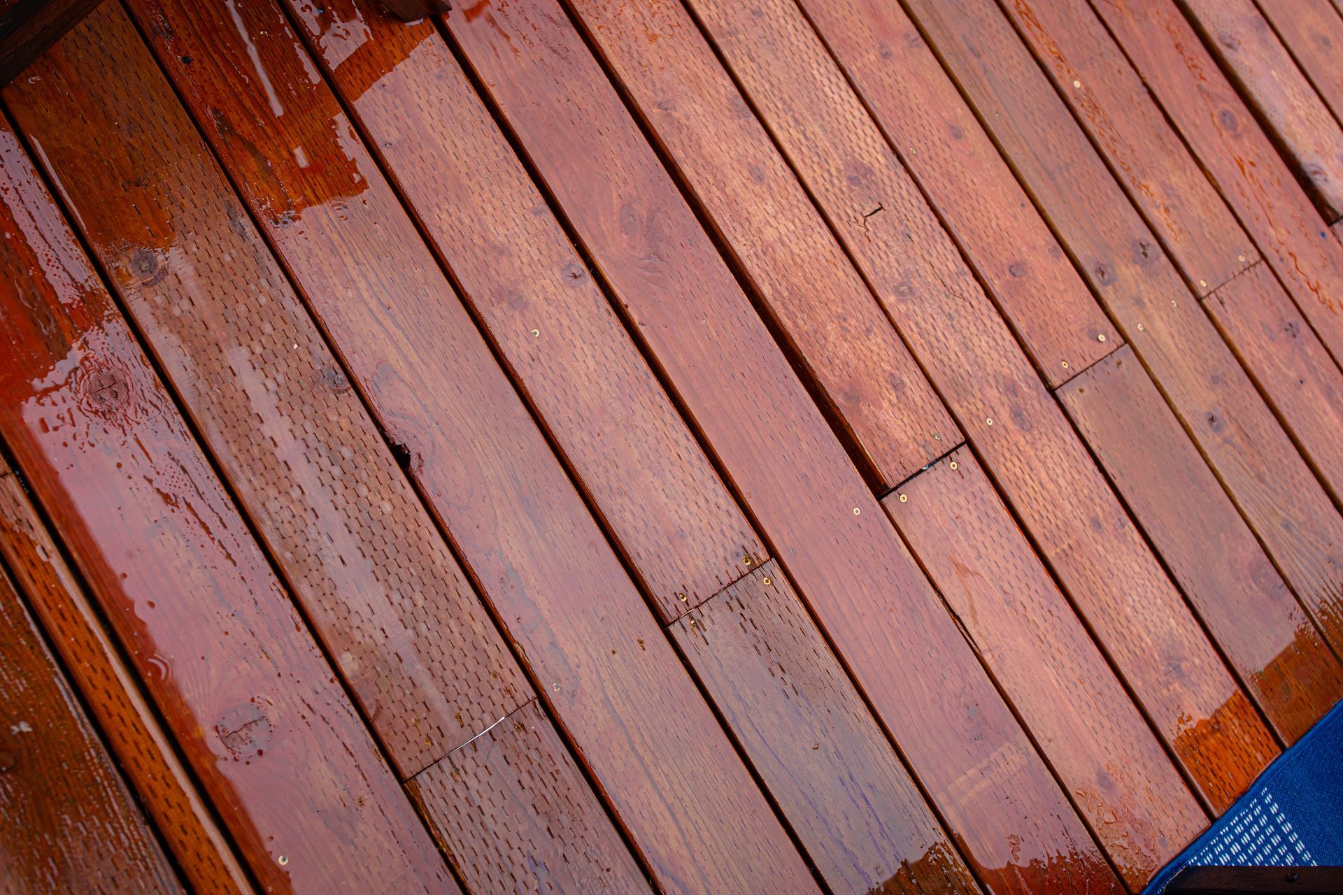 Diagonal view of wet, reddish-brown wooden deck boards.