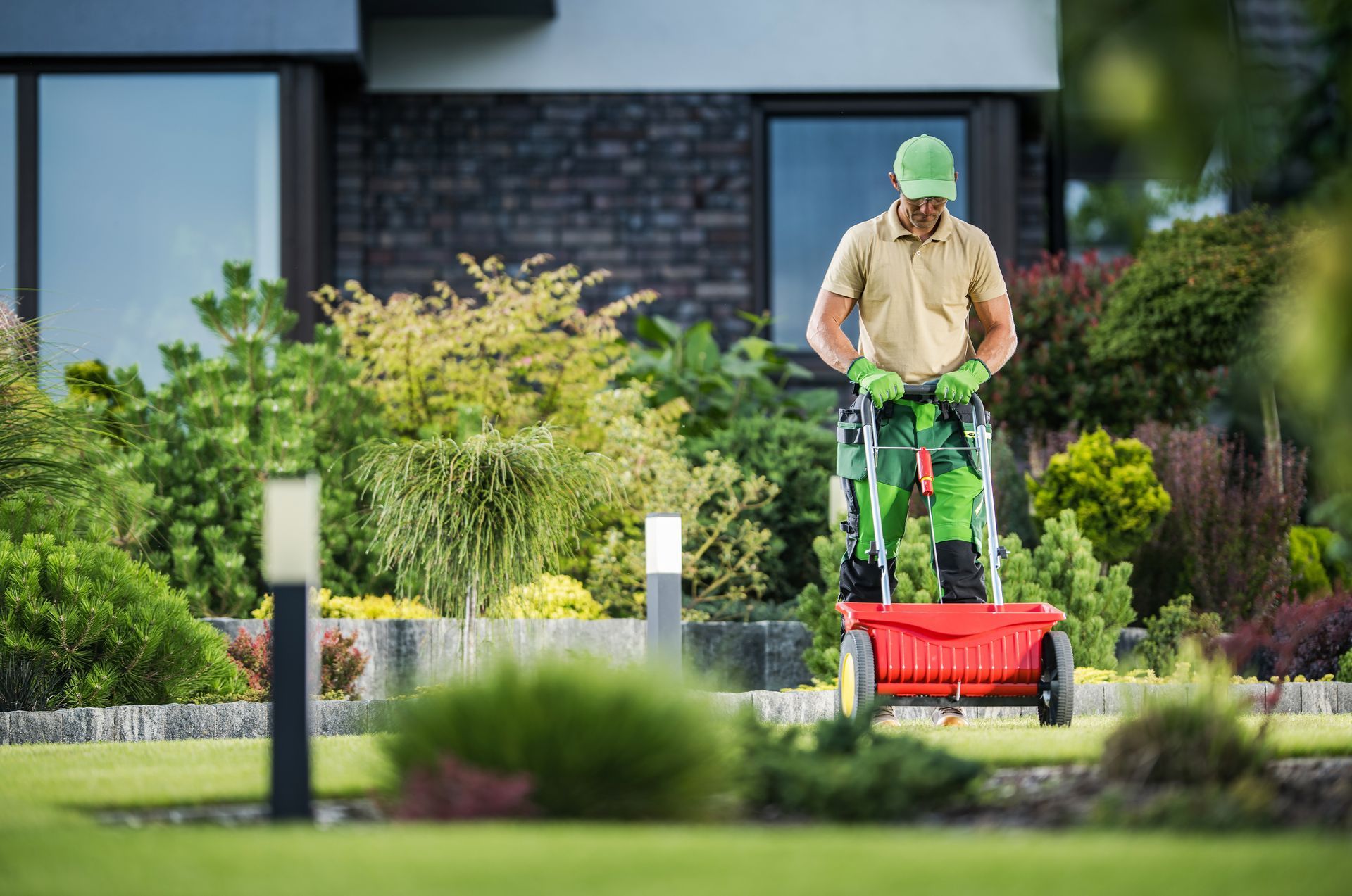 A lawncare professional distributes fertilizer on a customer's lawn