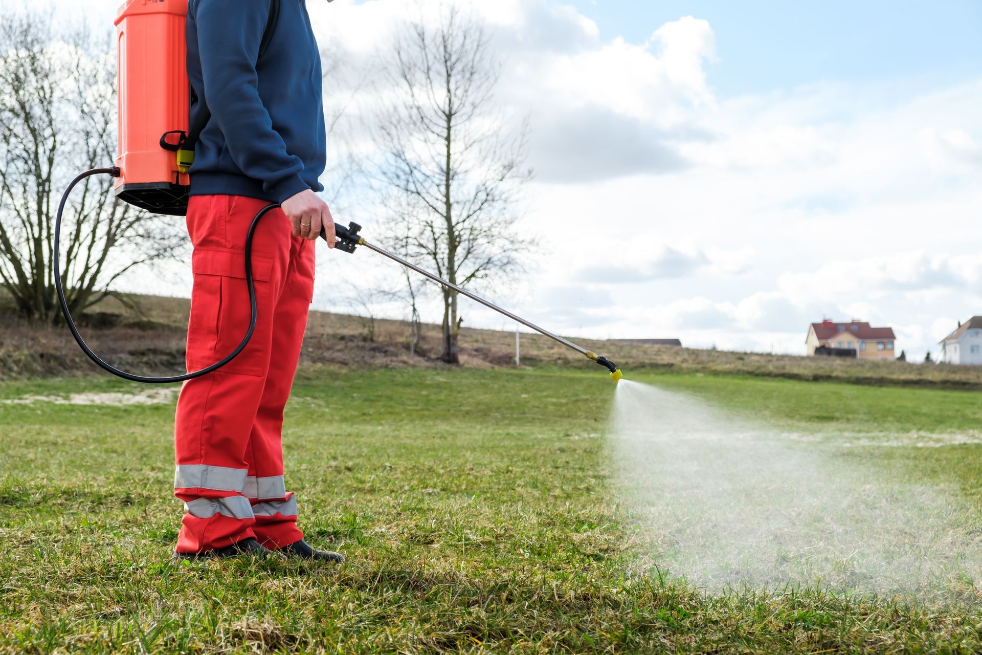 A lawncare professional applies liquid fertilizer to a lawn
