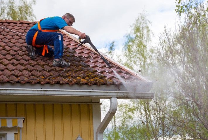 Jurupa Valley Ontario Pressure Washing technician cleaning roof and gutters