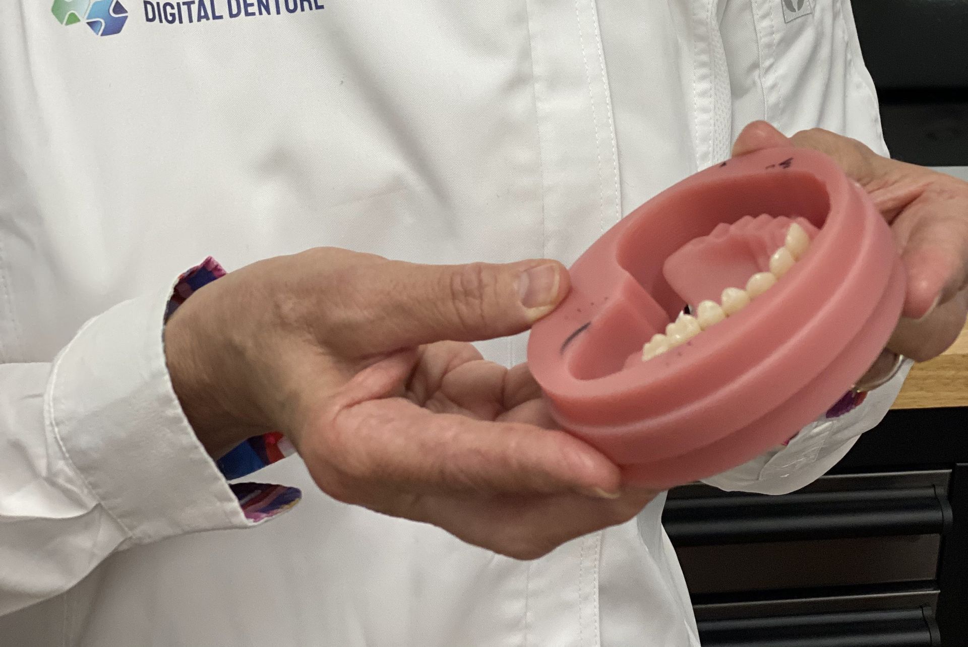 Person Holding a Pink Model of a Denture — My Denture Clinic in Benowa, QLD