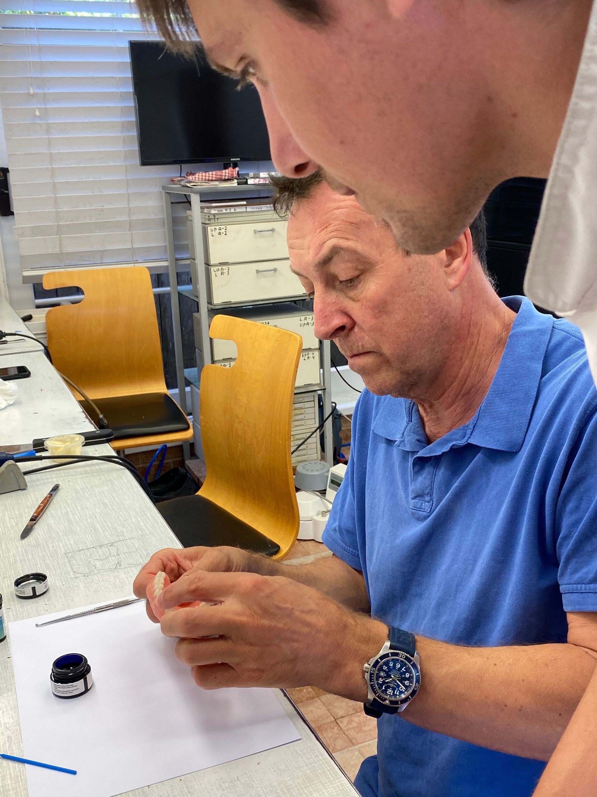 Two Men Fixing Dentures at a Desk — My Denture Clinic in Armidale, NSW