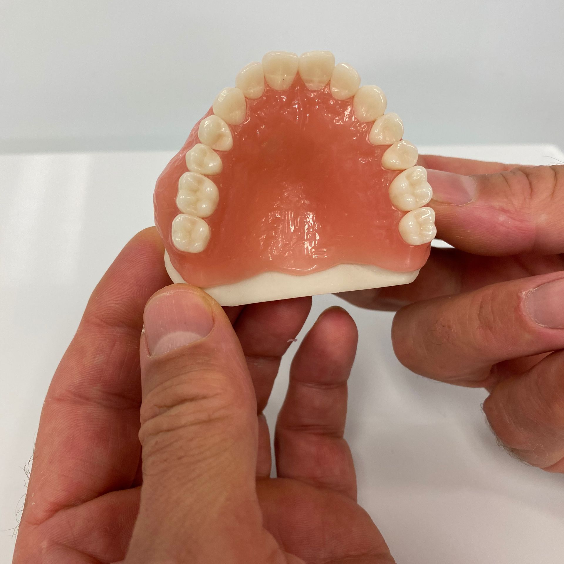 Person Holding a Set of Upper Dentures — My Denture Clinic in Benowa, QLD