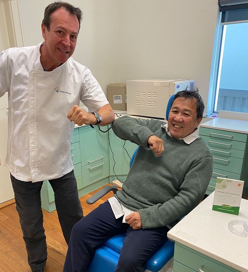 Doctor and Patient Doing Elbow Bump, Smiling, in a Dentist Office — My Denture Clinic in Benowa, QLD