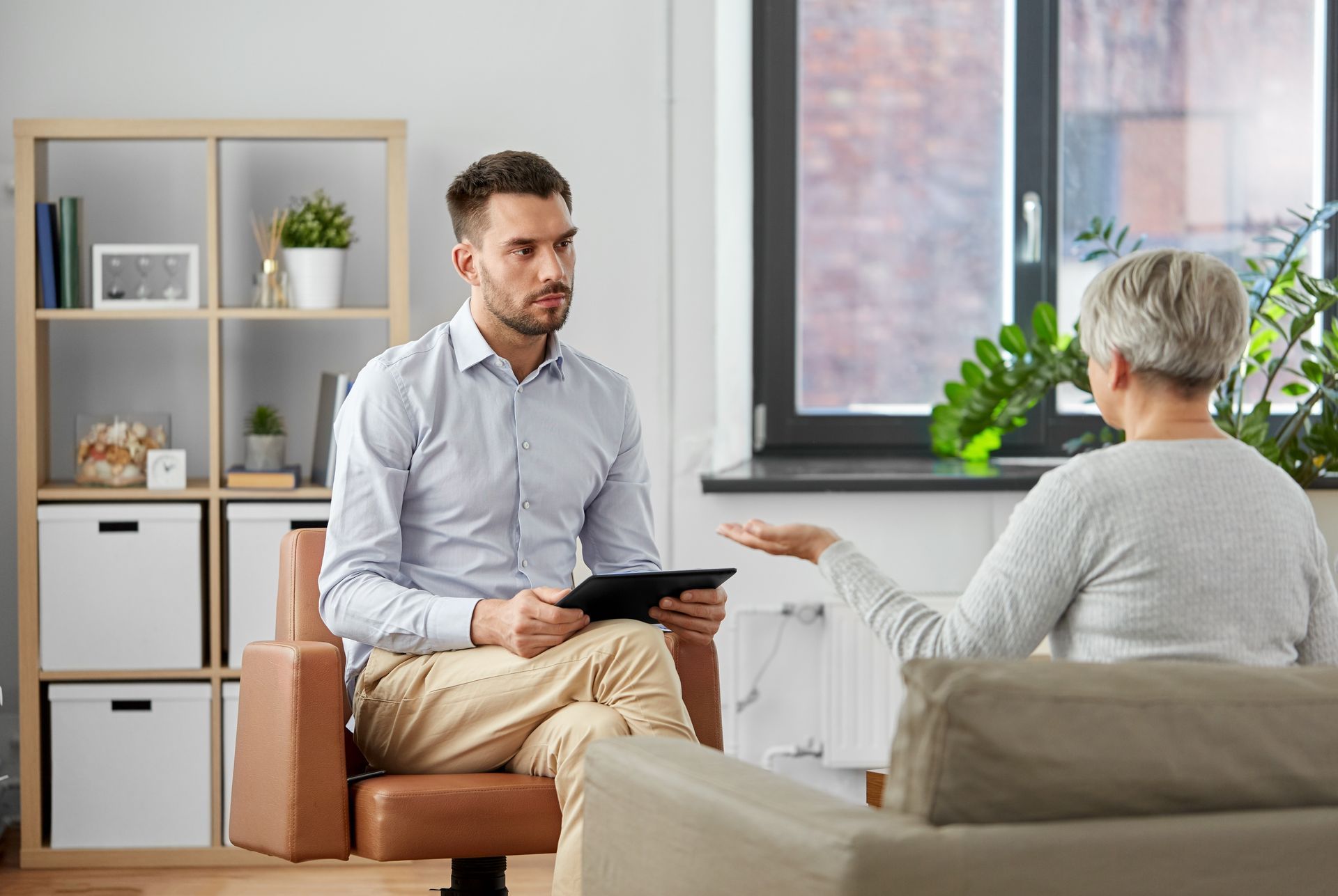 A man is sitting in a chair talking to an older woman.