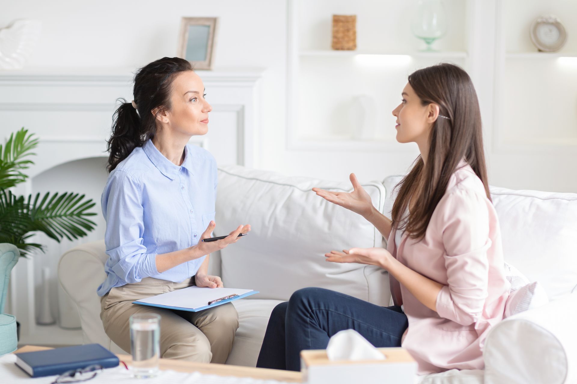A woman is sitting on a couch talking to a therapist.