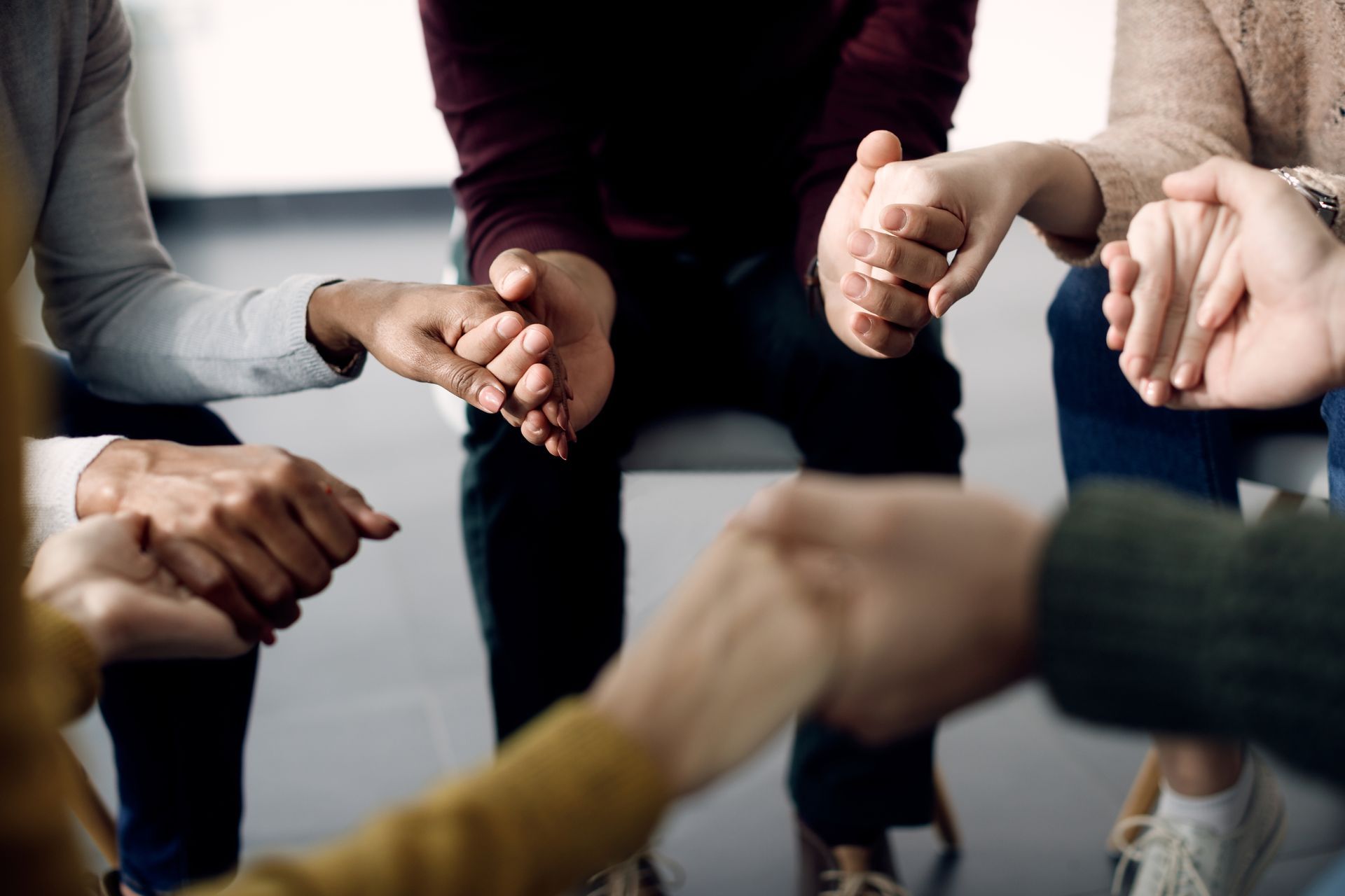 A group of people are sitting in a circle holding hands.