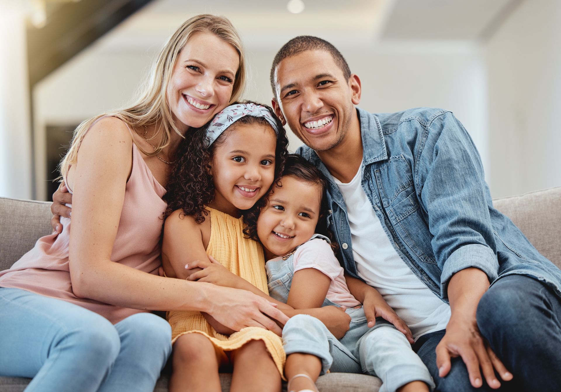 A family is sitting on a couch together and smiling for the camera.