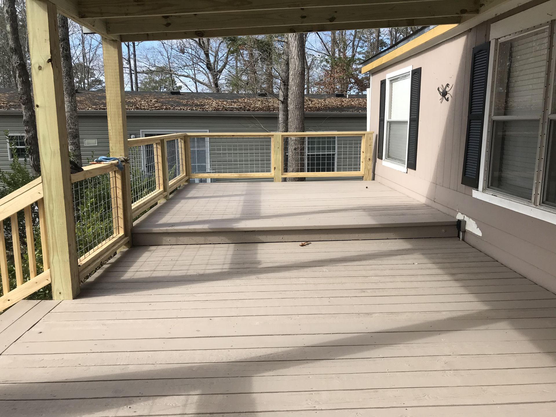 There is a large deck with a wooden railing on the side of the house.