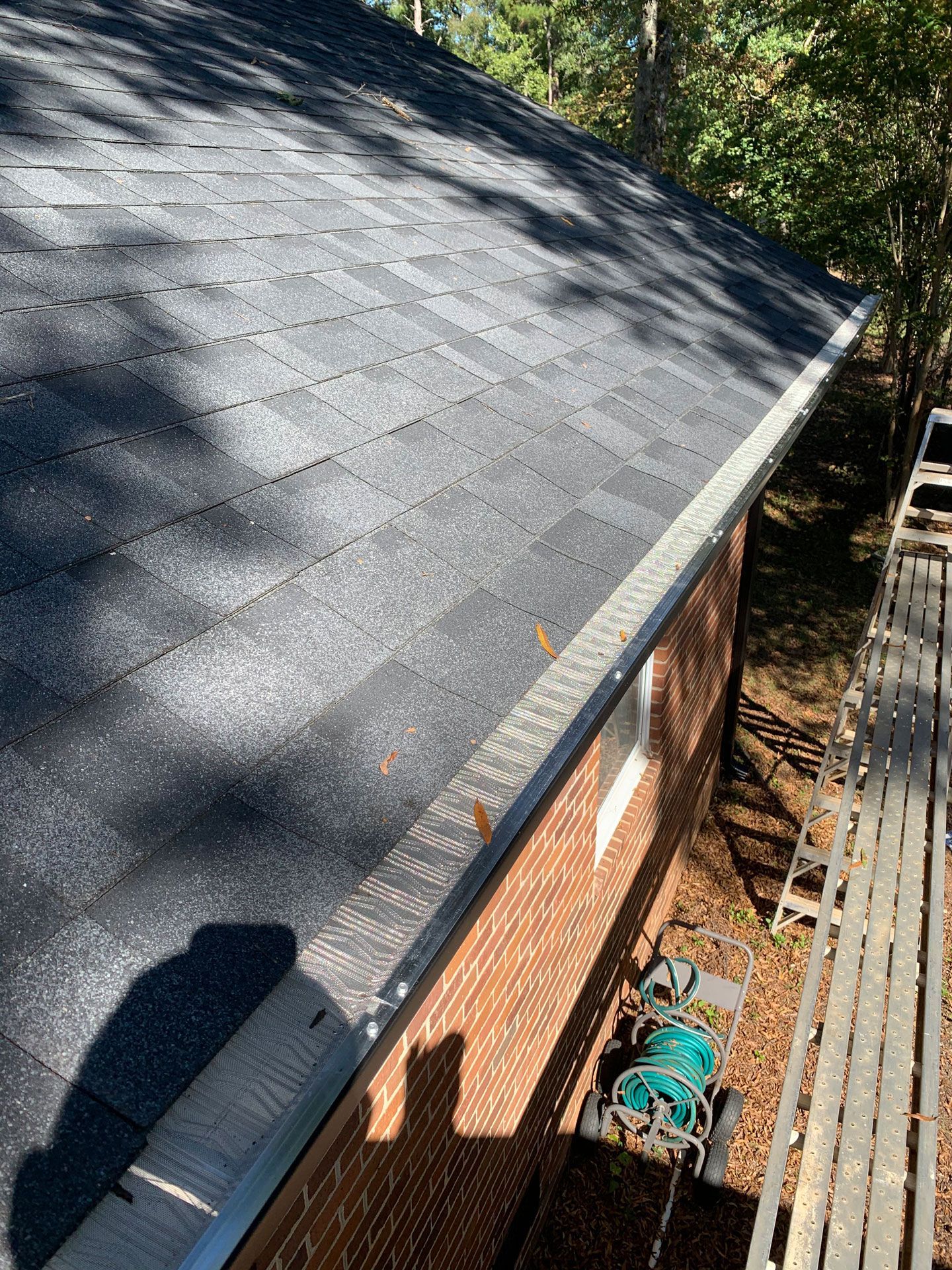 A brick house with a black roof and a metal gutter.
