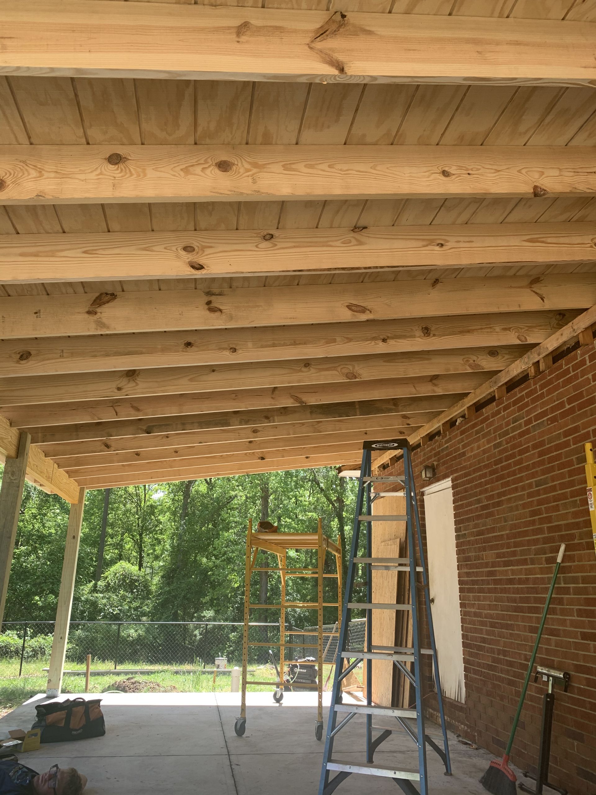 A ladder is sitting under a wooden ceiling in a building under construction.