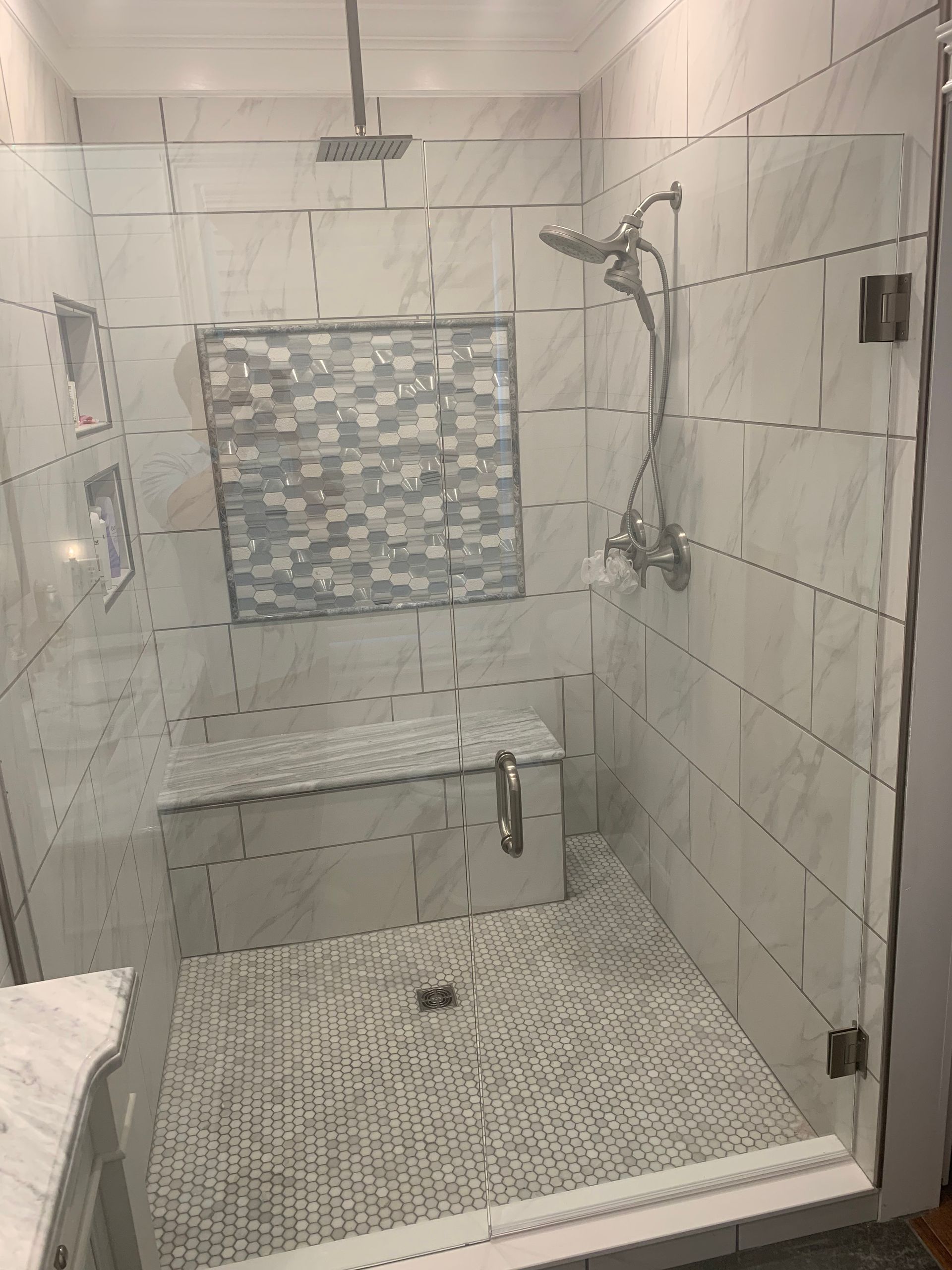 A bathroom with a walk in shower and a bench.