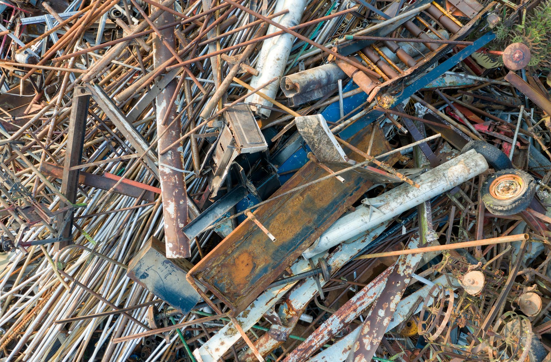 Pile of scrap metal: rusty rods, metal sheets, and other debris in various colors and shapes.