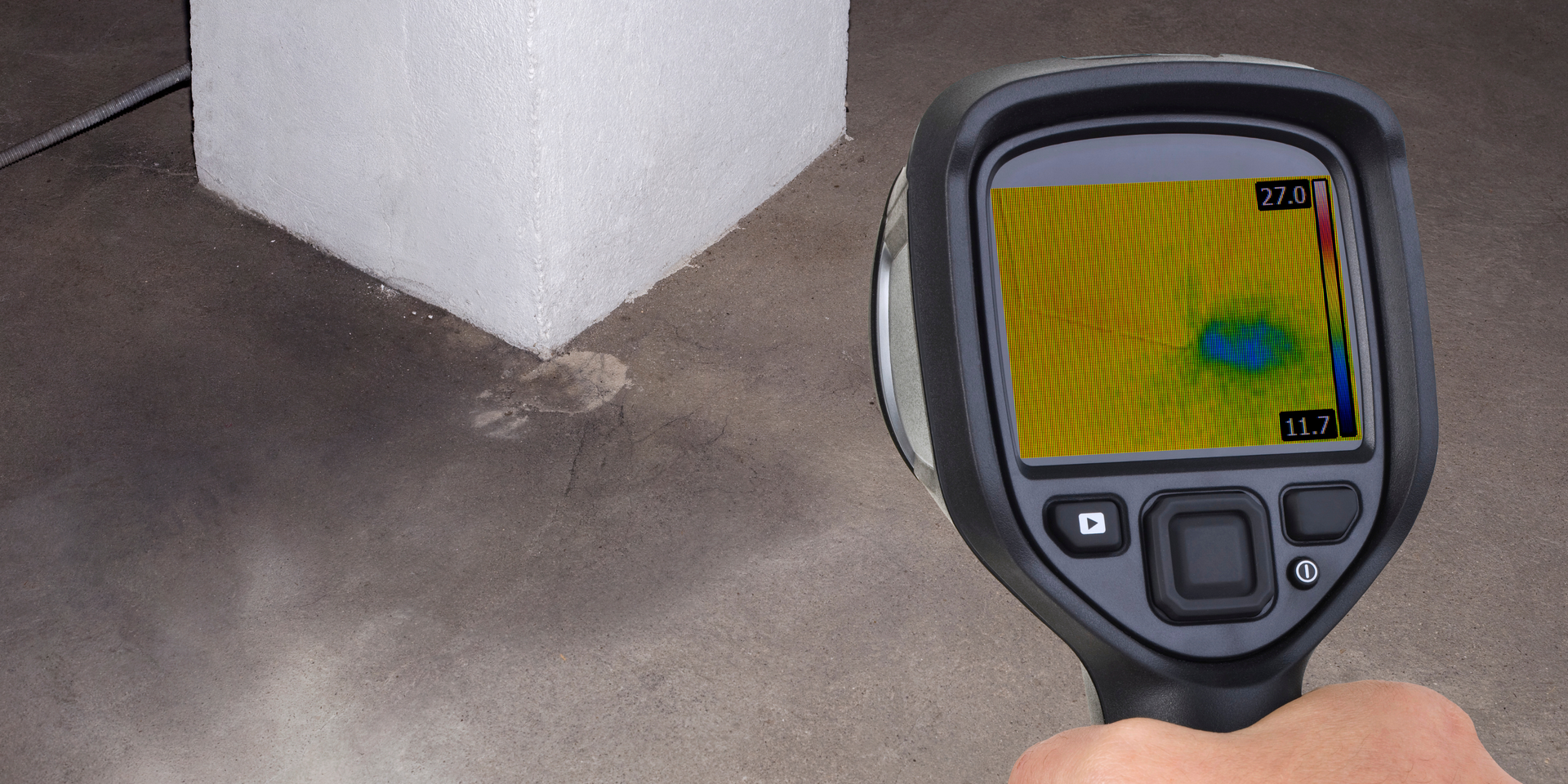 Thermal camera detecting a cold spot on a concrete floor near a white wall.