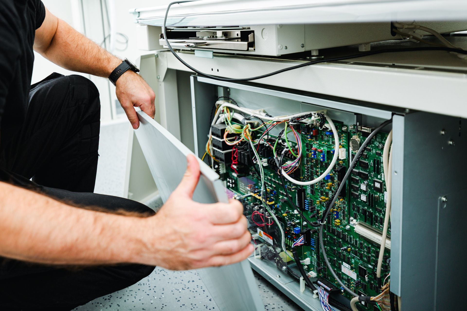 A man is removing the metal cover of a medical X-ray unit for technical inspection.