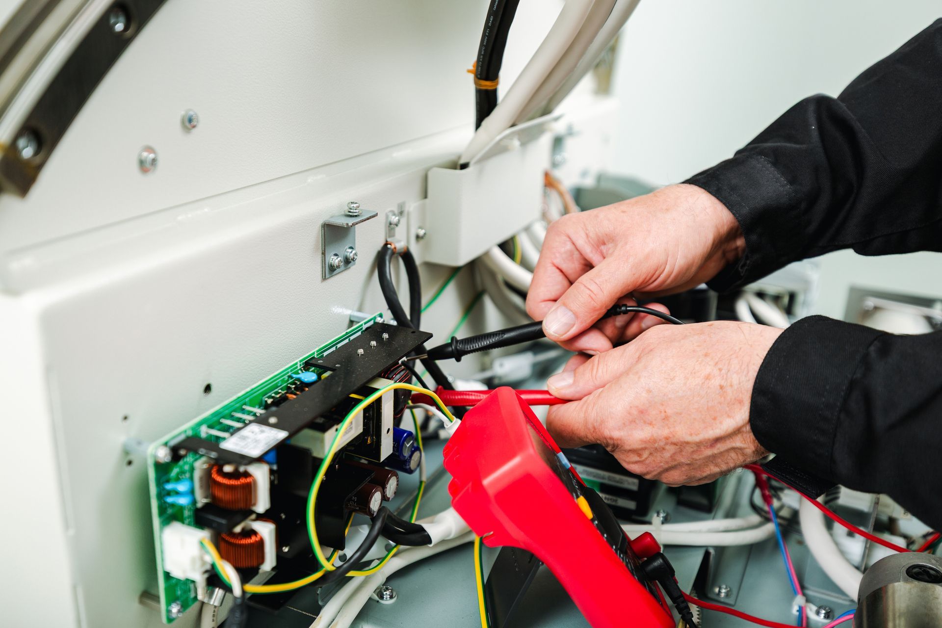 A man is measuring the voltage on an electronic board of an X-ray machine. A man is measuring the voltage on an electronic board of an X-ray machine.