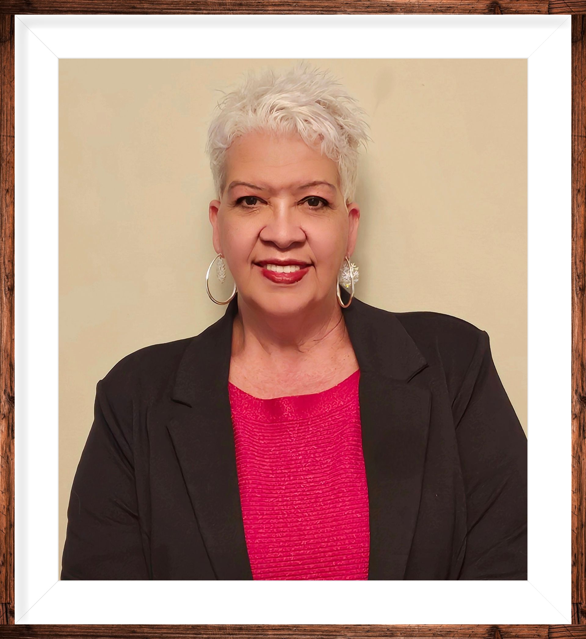 A woman is sitting at a desk with a laptop and a vase of flowers.