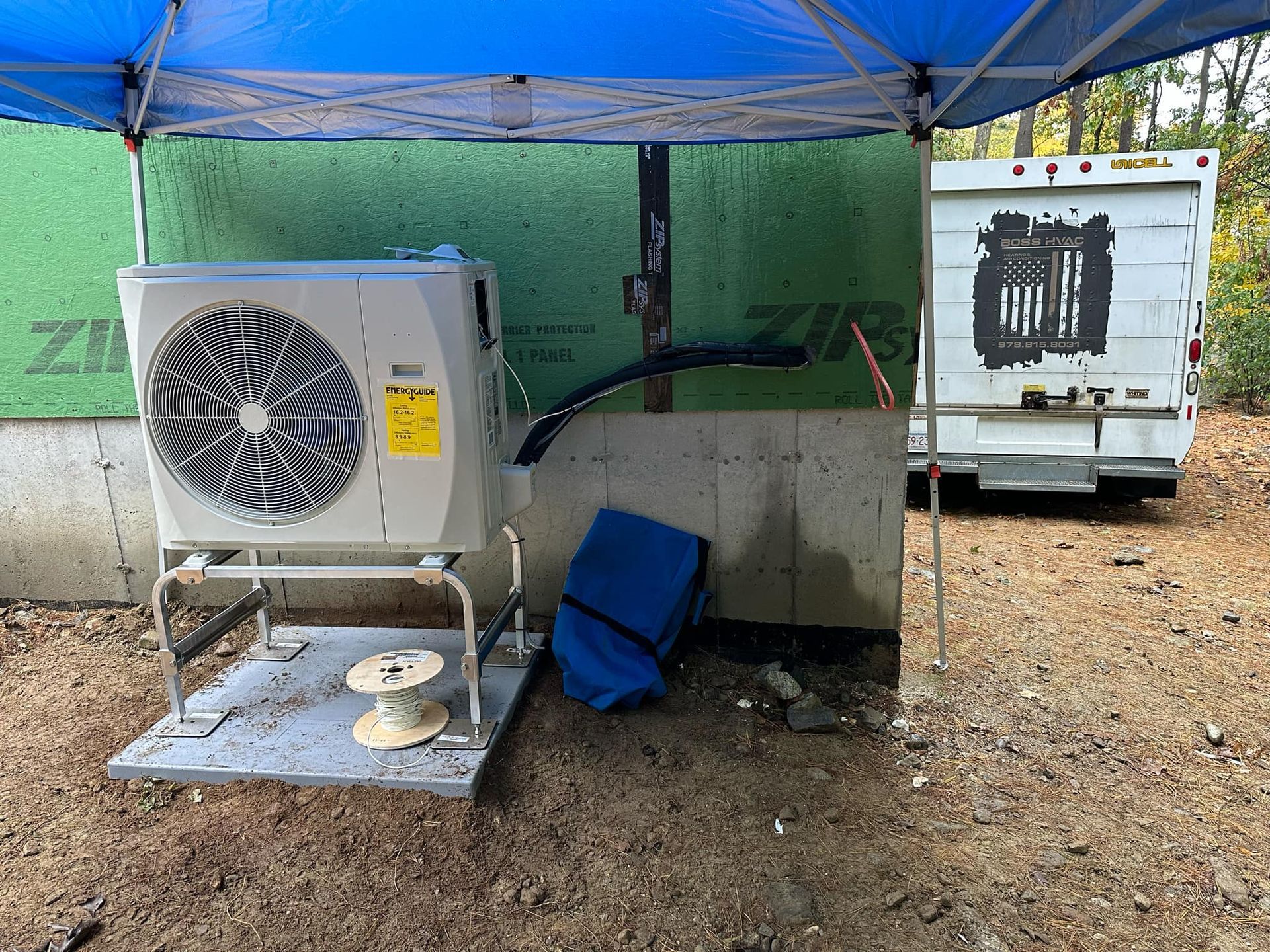 An air conditioner is sitting under a blue tent