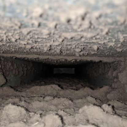 A close up of a dirty air vent in a building.