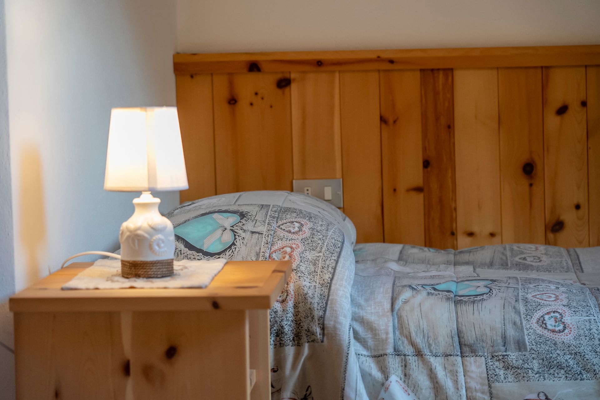 Una camera da letto con letto, comodino, lampada e testiera in legno.