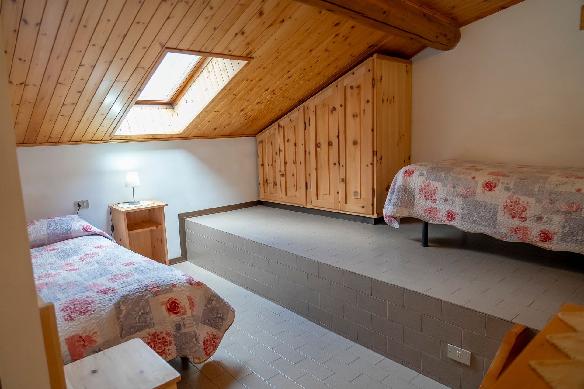 Una camera da letto con due letti e un lucernario nel soffitto.