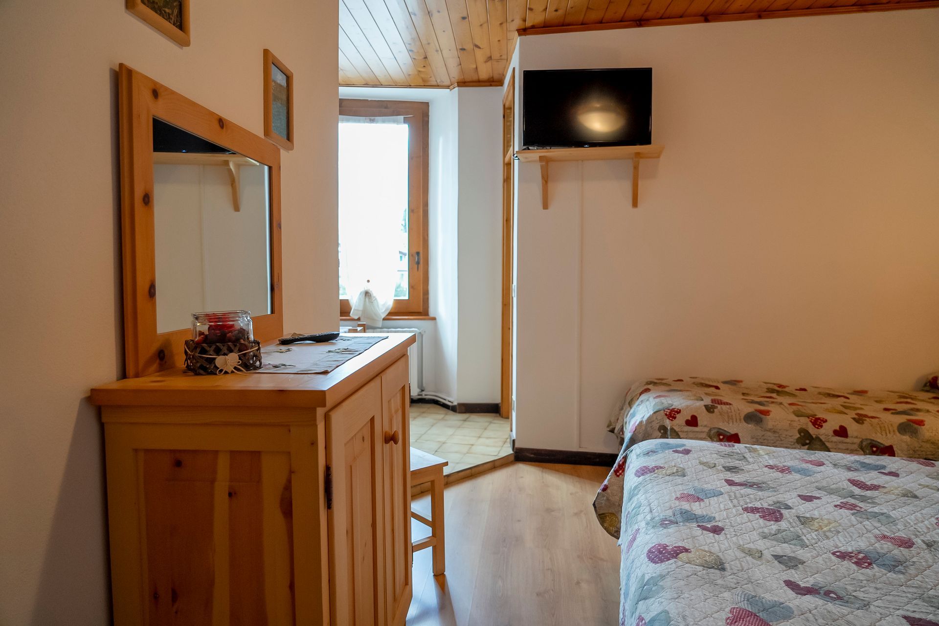 Una camera da letto con due letti, uno specchio e una televisione.