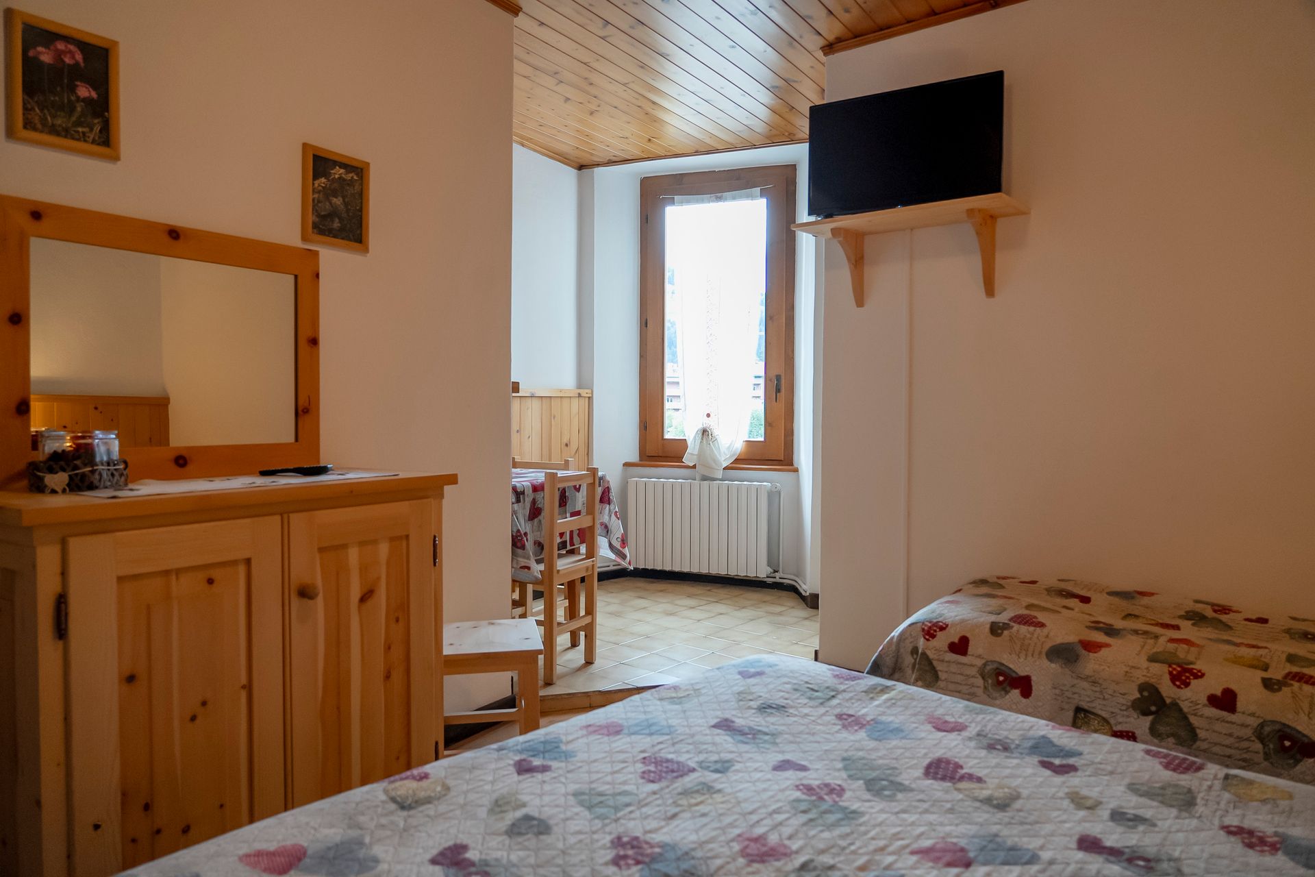 Una camera da letto con letto, cassettiera, specchio e televisione.