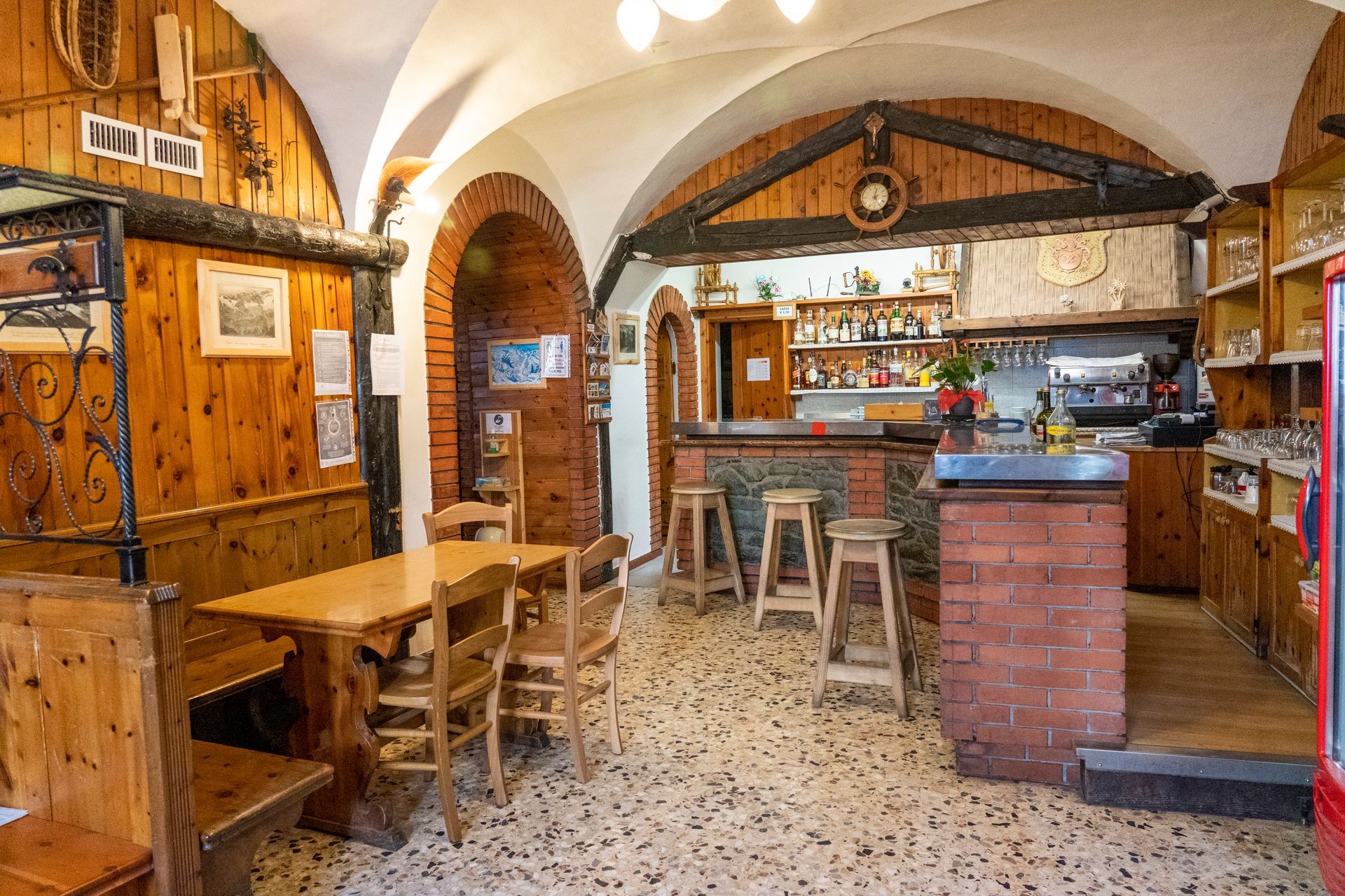 Un ristorante con tavoli e sedie in legno e un bar in mattoni.