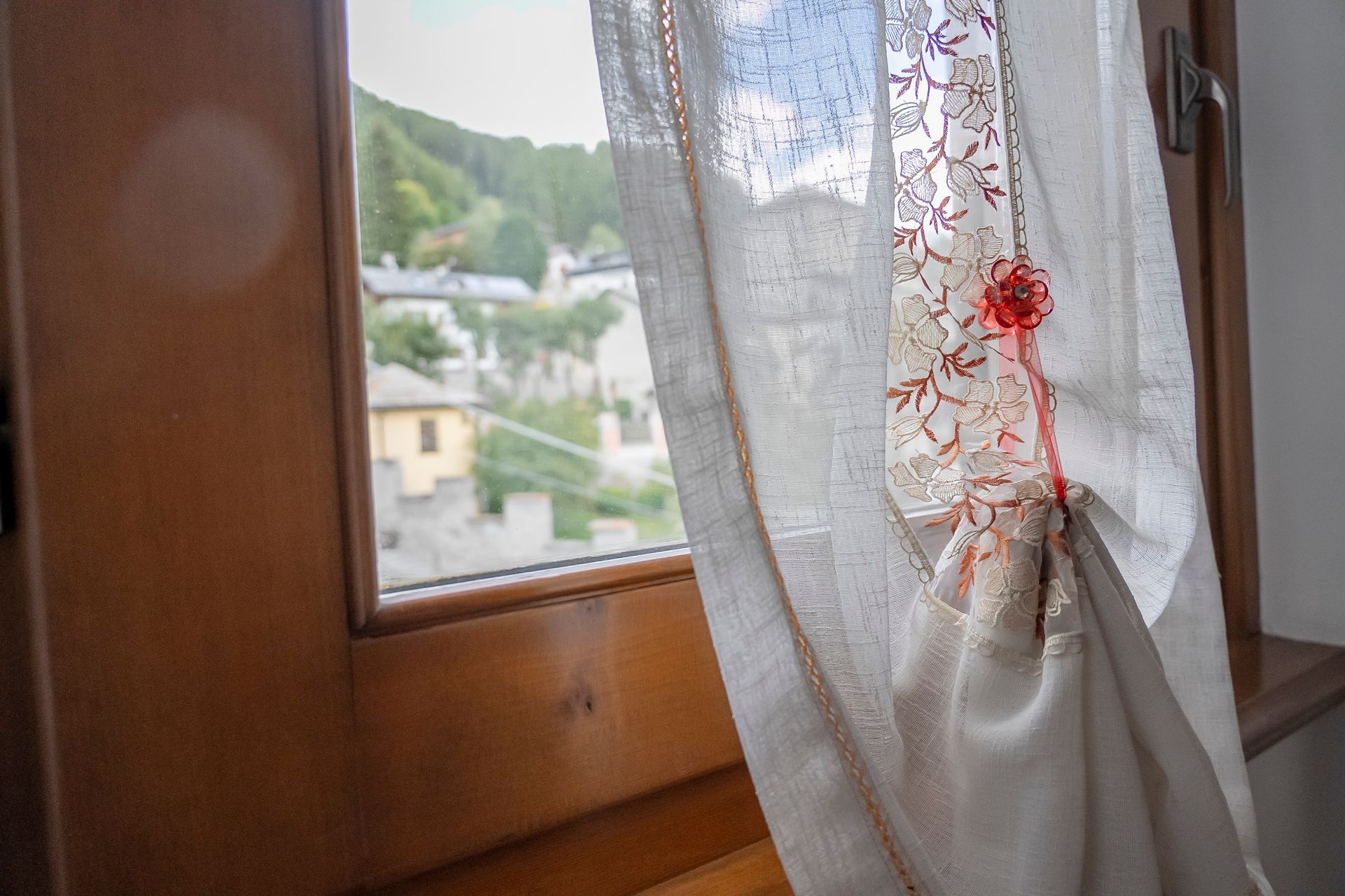 Una tenda bianca è appesa a una finestra di legno.