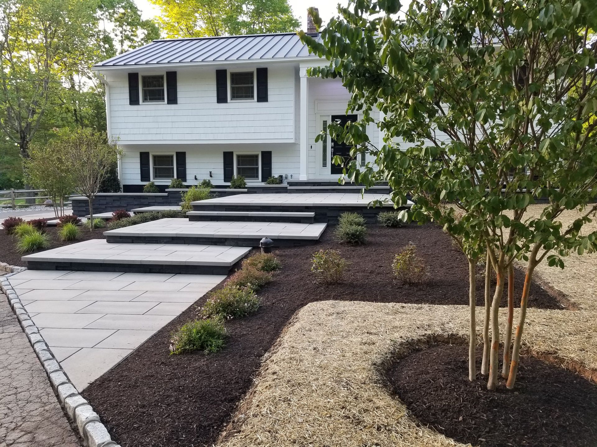 A white house with a black roof and steps leading up to it.
