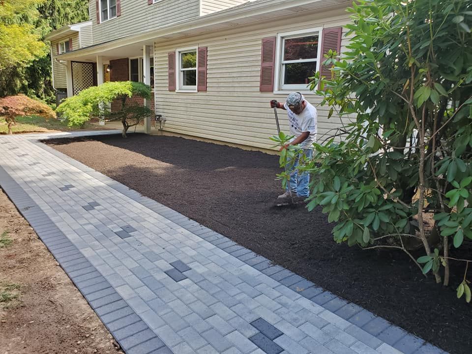 A man is laying a brick walkway in front of a house.