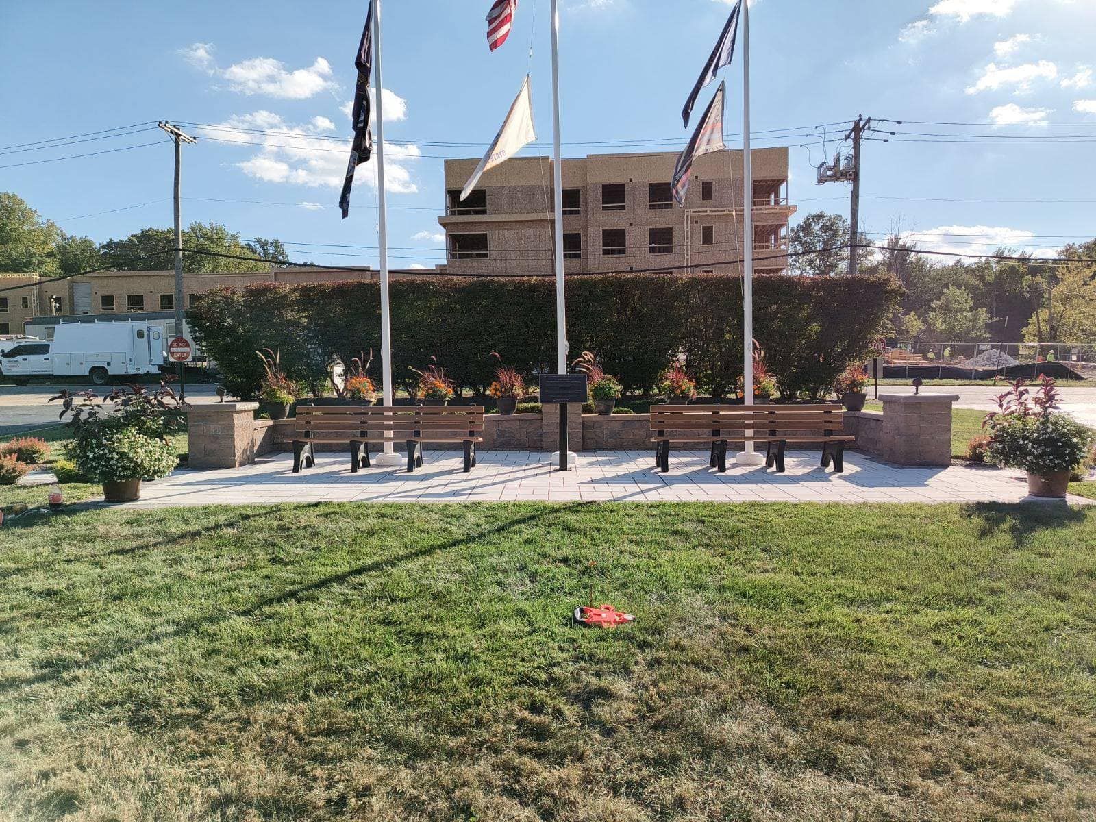 A park with flags and benches in front of a building under construction