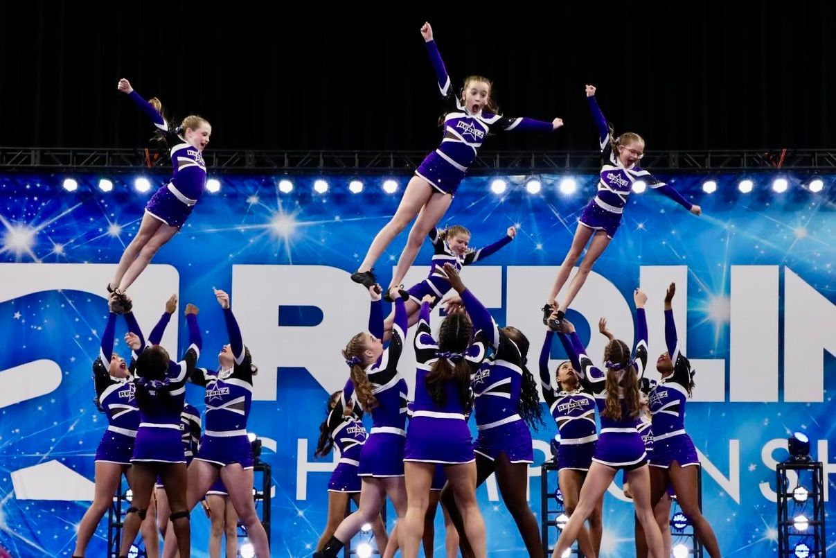 A group of cheerleaders are performing on a stage in front of a banner that says carolina