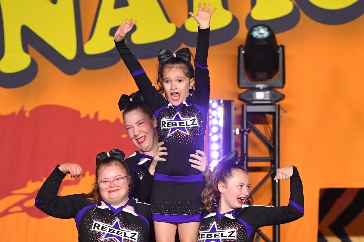 A group of cheerleaders are standing on a stage with their arms in the air