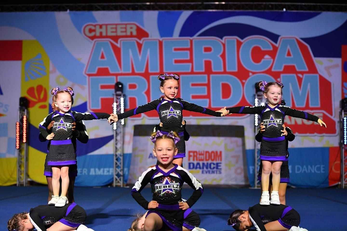 A group of cheerleaders are performing in front of a sign that says cheer america freedom