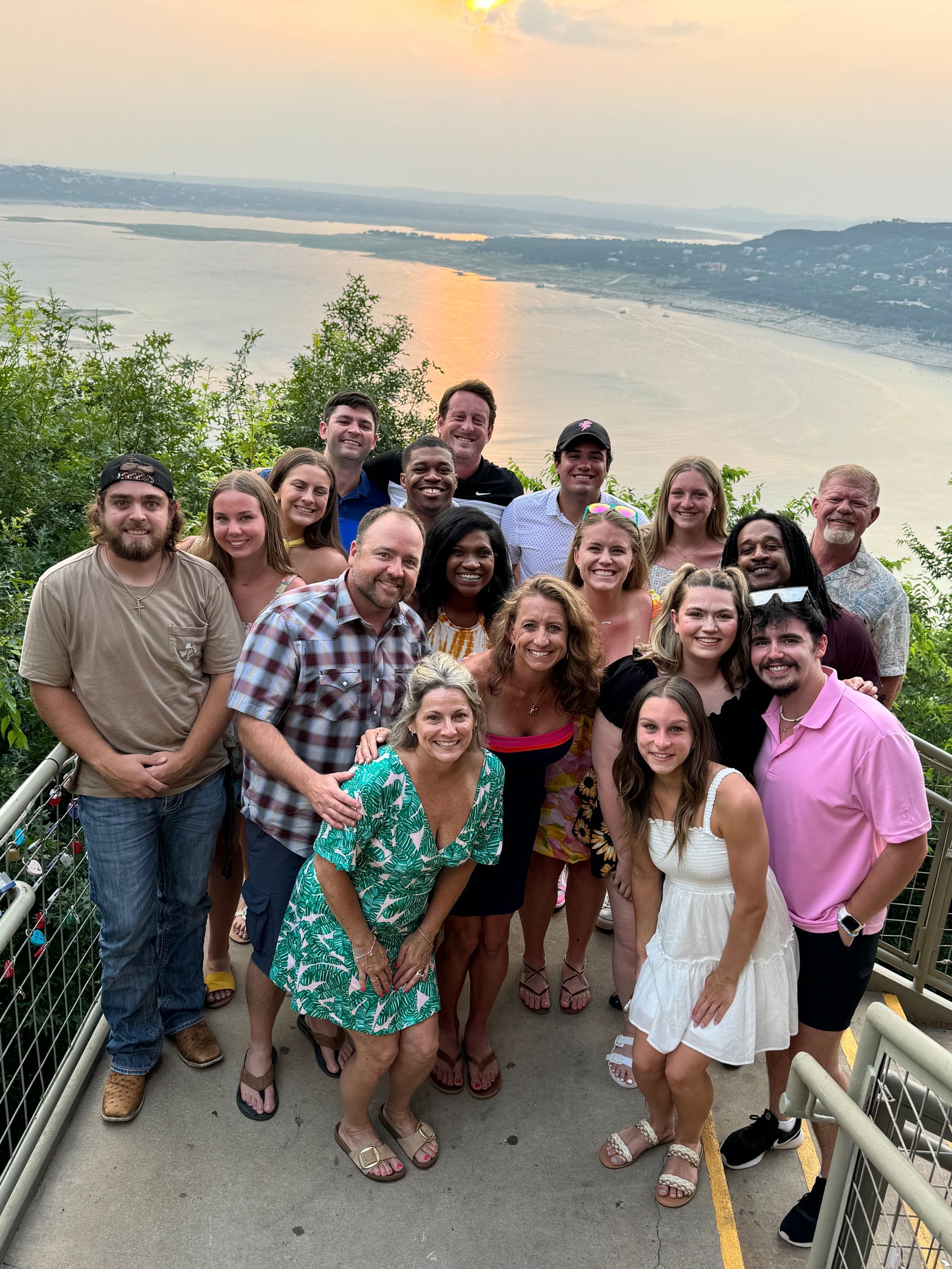 A group of people are posing for a picture on a balcony overlooking a body of water.