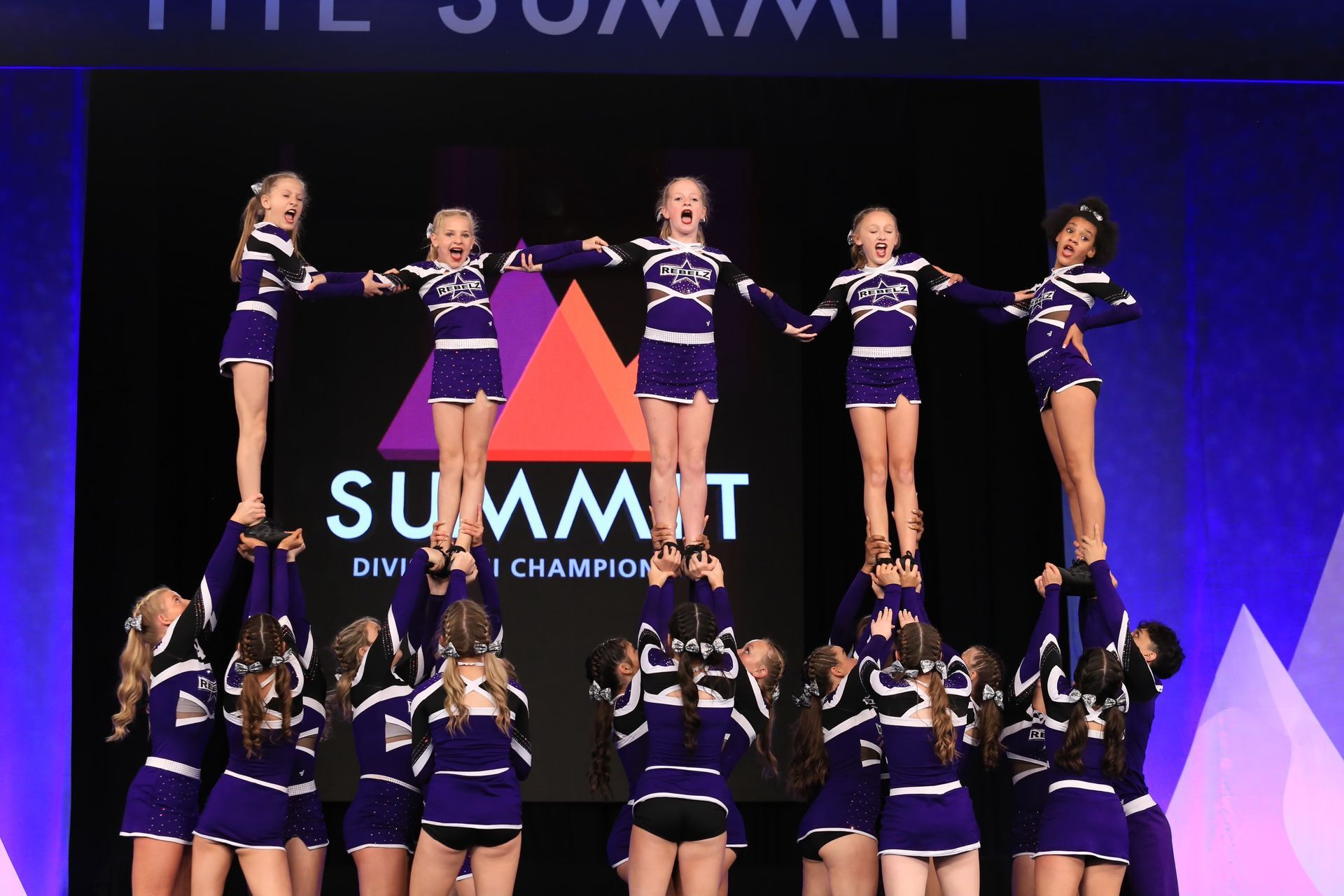 A group of cheerleaders are performing in front of a summit sign.