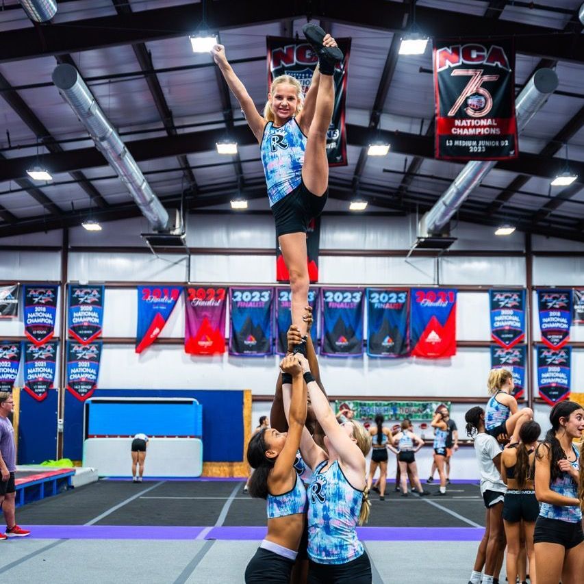 A cheerleader is being lifted in the air in front of a sign that says ncaa