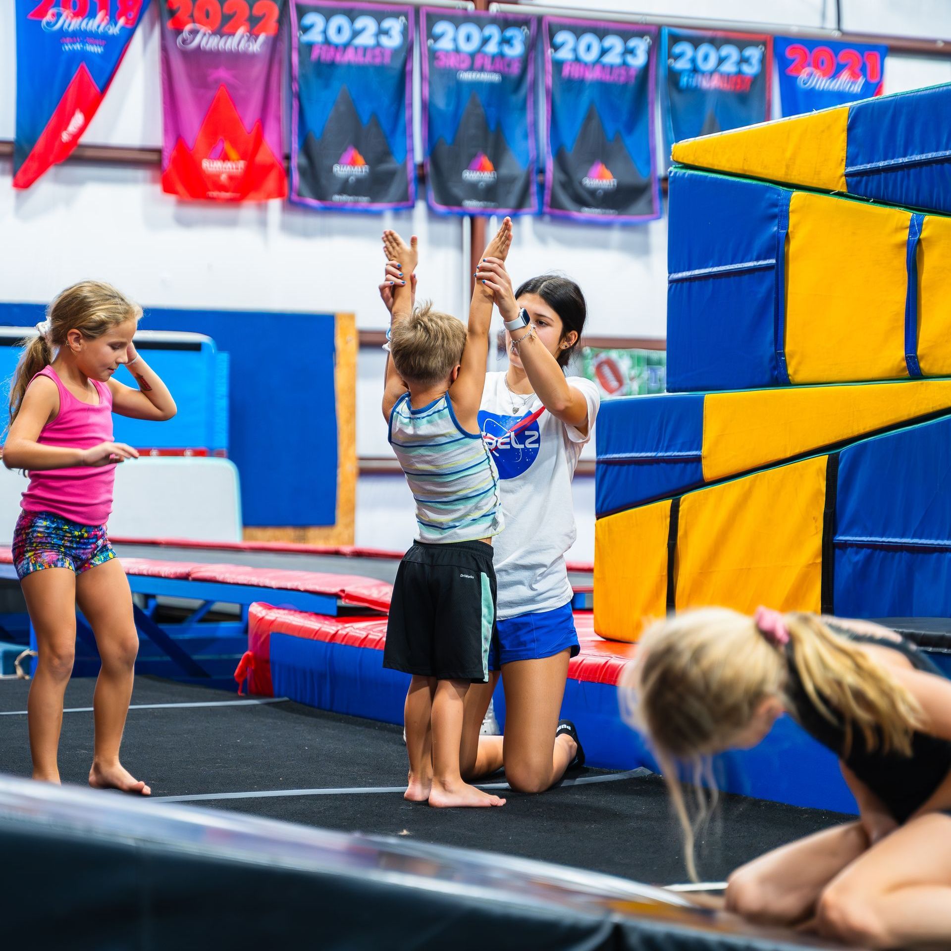 A group of children are playing in a gym with a sign that says 2023 on it