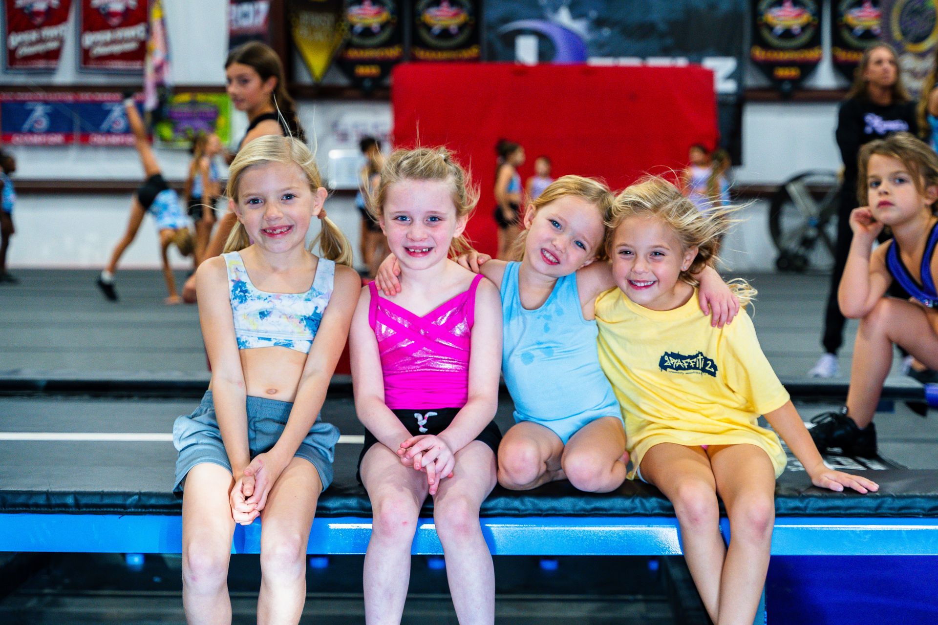 A group of young girls are sitting on a bench in a gym.