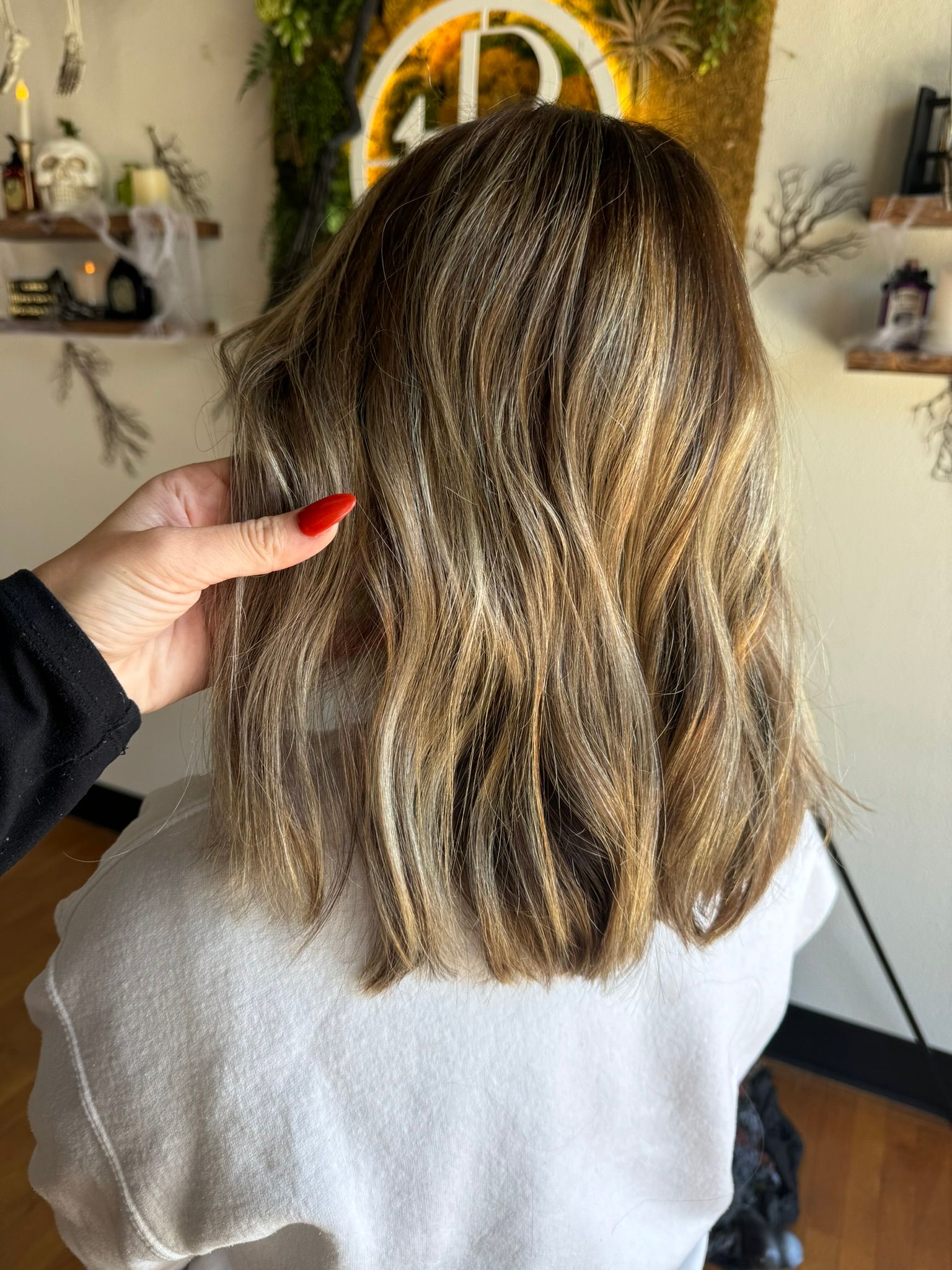 A woman with red nails is getting her hair done in a salon